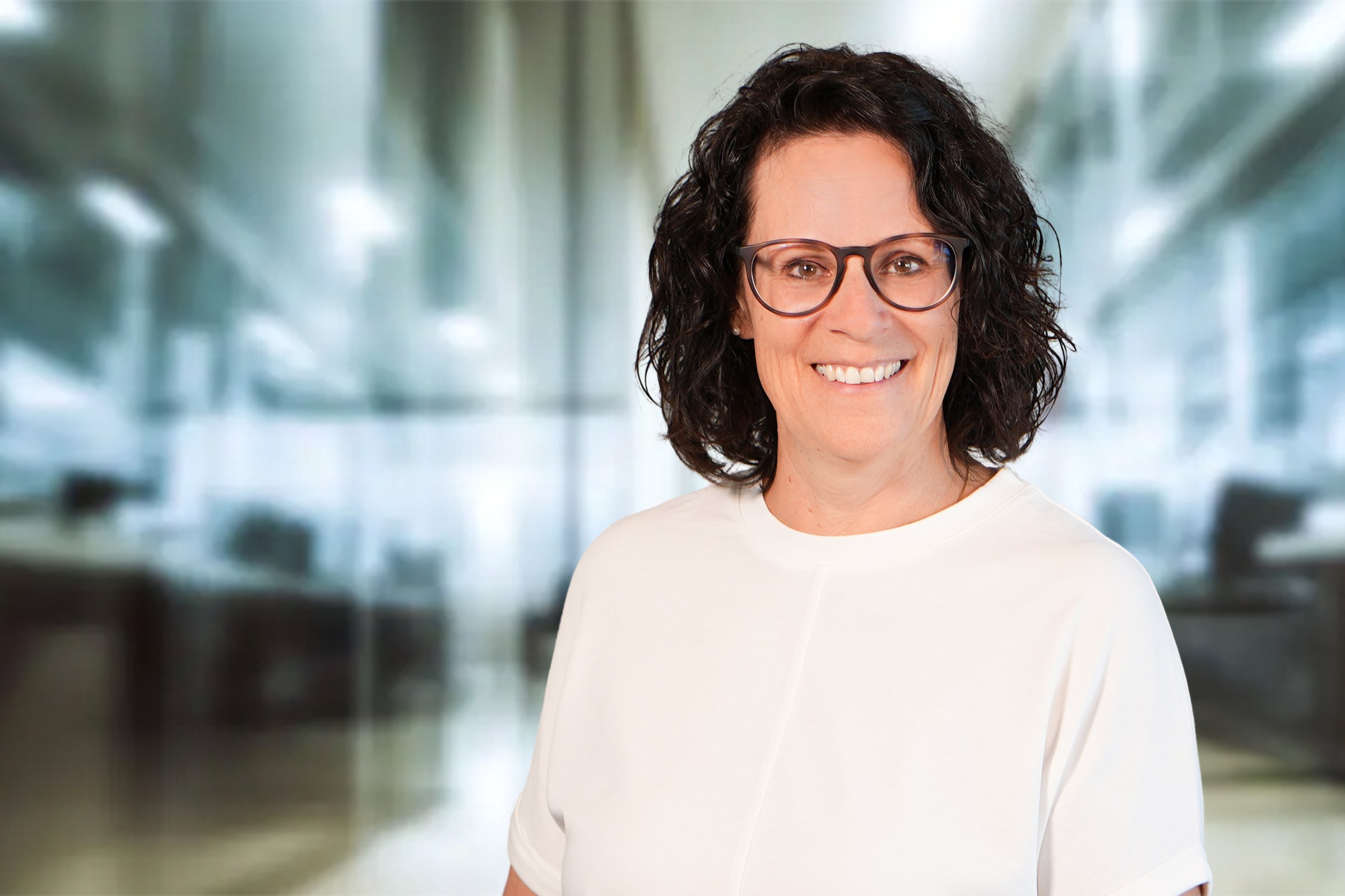 Christina Bauer, Frau mit dunklen halblangen Haaren und Brille mit weißem Blusenshirt