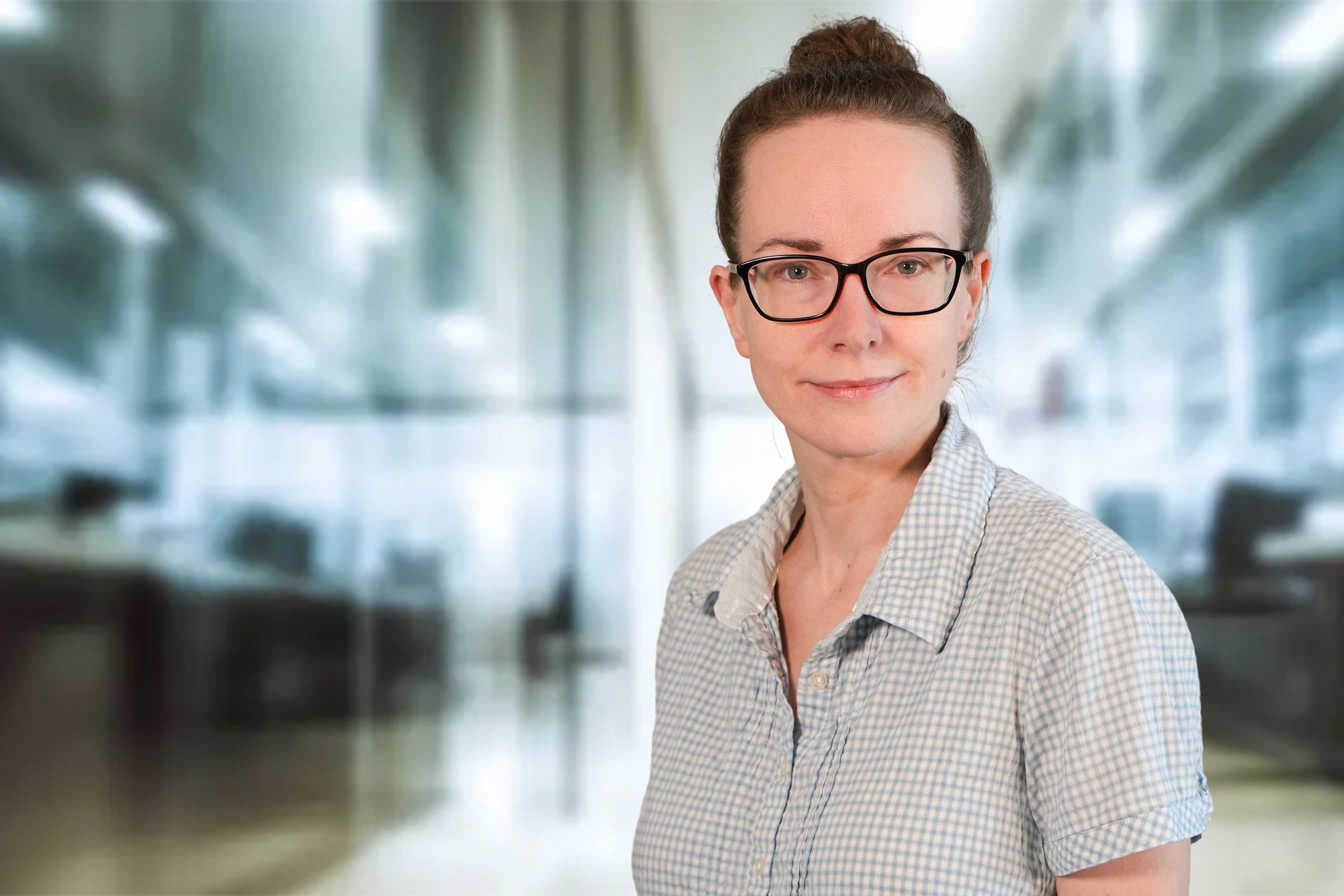 Christine Meyhöfer, Frau mit braunen Haaren und Dutt in grauweiß karierter Kurzarmbluse