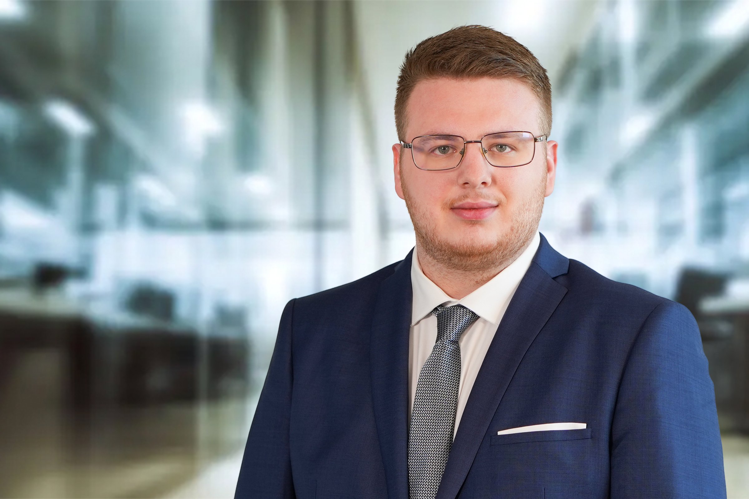Cristian Stanila, junger Mann mit mittelblonden, kurzen Haaren und Dreitagebart mit blauem Sakko, weißem Hemd und Krawatte