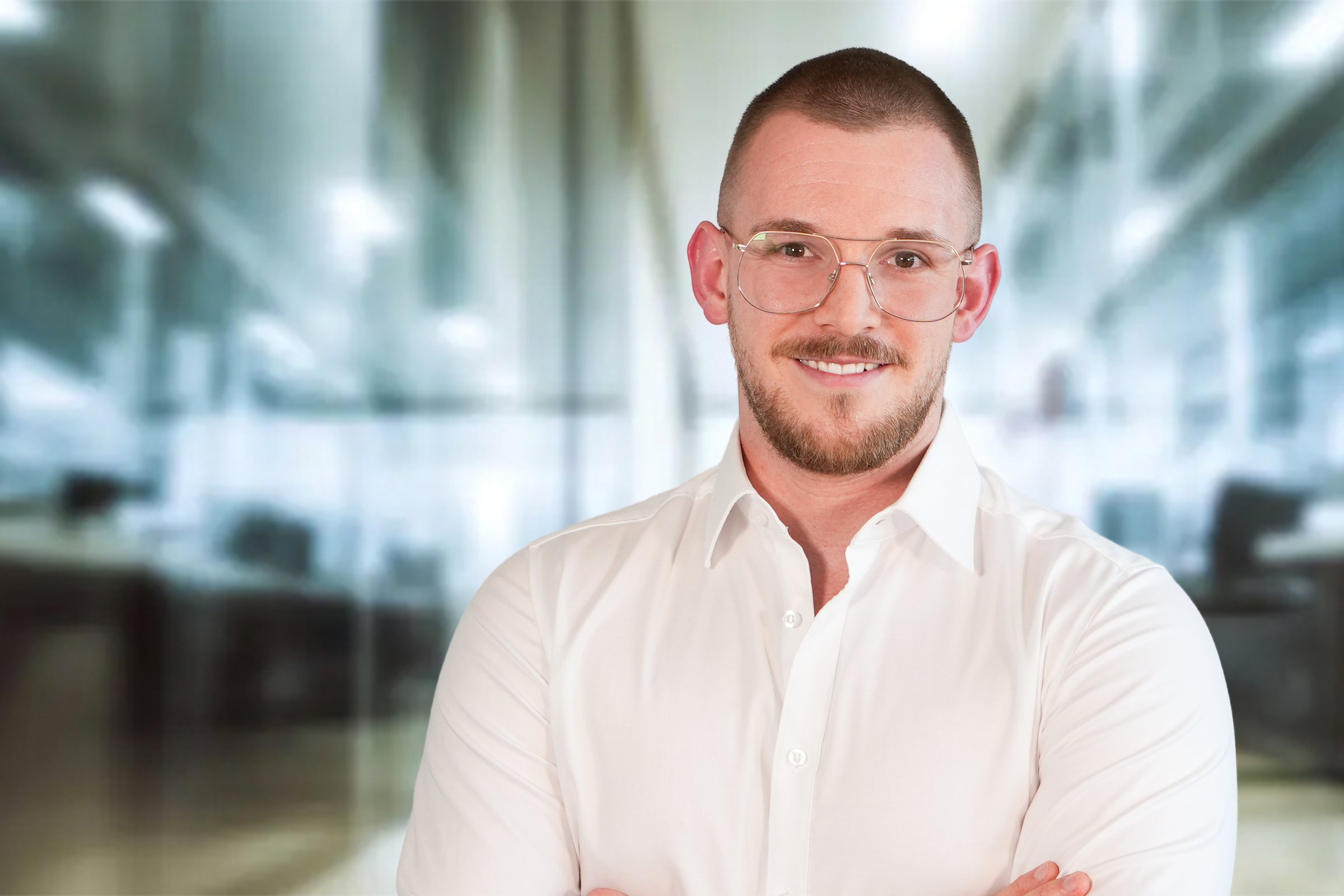 Dennis Kuschel, junger Mann mit mittelblonden, kurzen Haaren und Brille im weißem Hemd