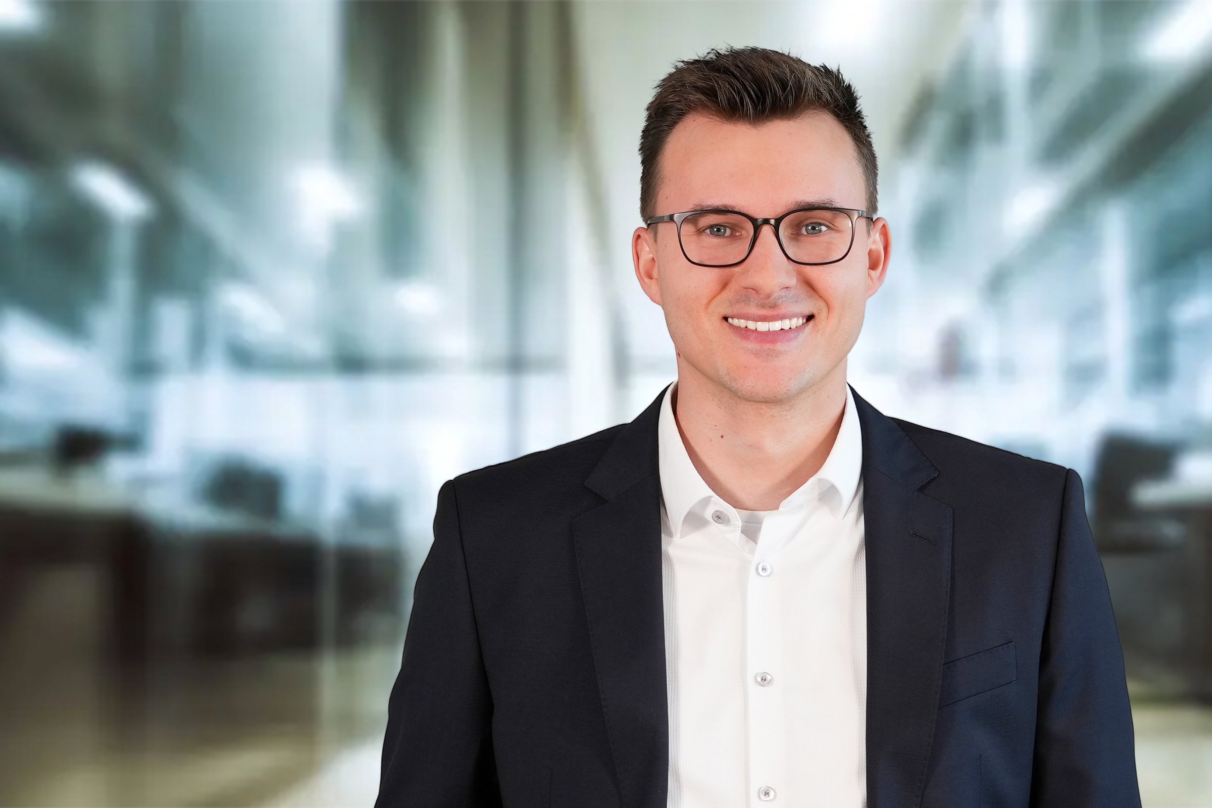Steuerberater Joshua Hary, Mann mit dunklen kurzen Haaren und weißem Hemd mit dunkelblauem Sakko