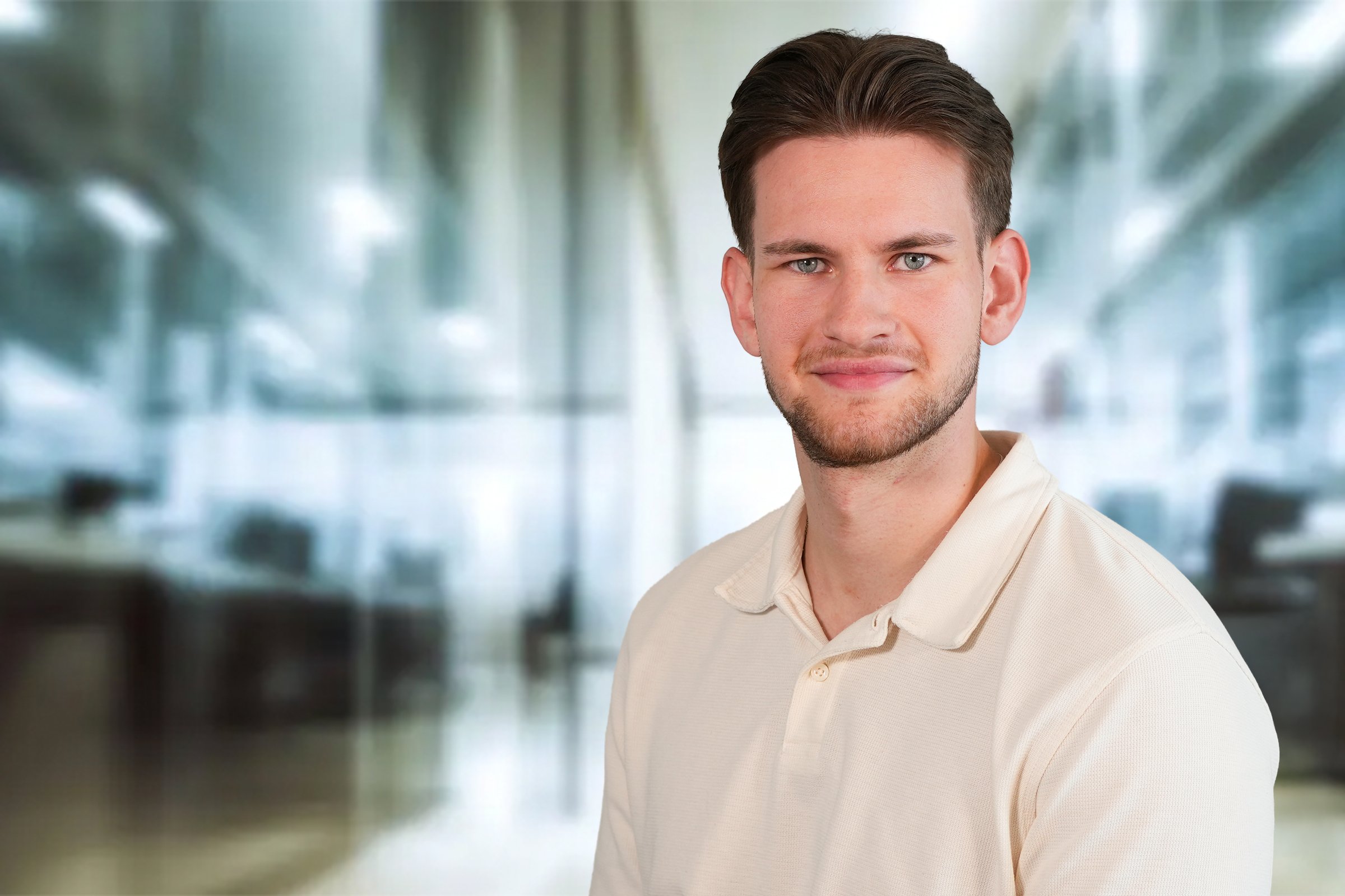 Simon Delz, junger Mann mit dunklen, nachhinten gekämten kurzen Haaren und Dreitagebart im beigefarbenen Poloshirt